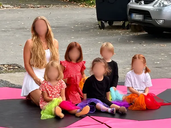 Kindertanzgruppe mit Trainerin auf Matten im Freien
